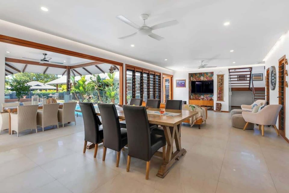 Dine in style in the open-plan dining area, where a wooden table with leather seating for six sits against the backdrop of tropical greenery.