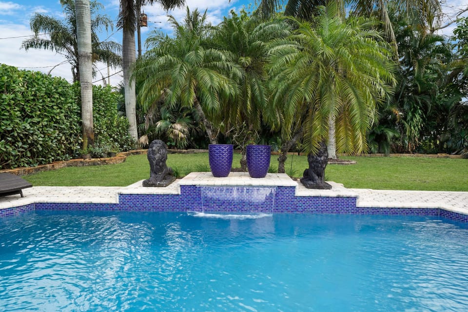 This lush, tropical sanctuary features a large, sparkling pool with cascading waterfalls, creating a tranquil, resort-like ambiance.