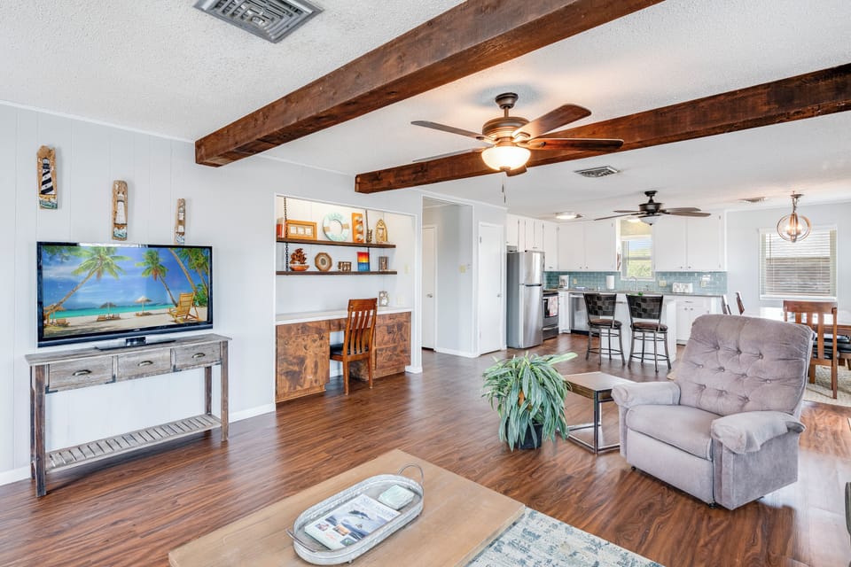 Relax in this spacious open-concept living area with exposed wooden beams, comfortable seating, and modern kitchen—your perfect home base for coastal getaways.
