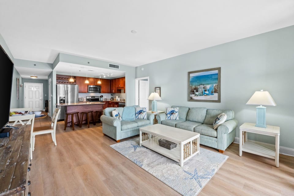 Open-concept living area with coastal-inspired decor and a fully equipped kitchen.