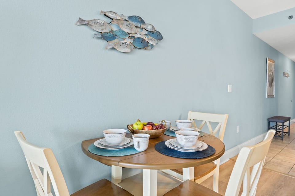 Cozy dining area with a round wooden table set against a soft blue wall featuring decorative fish art.