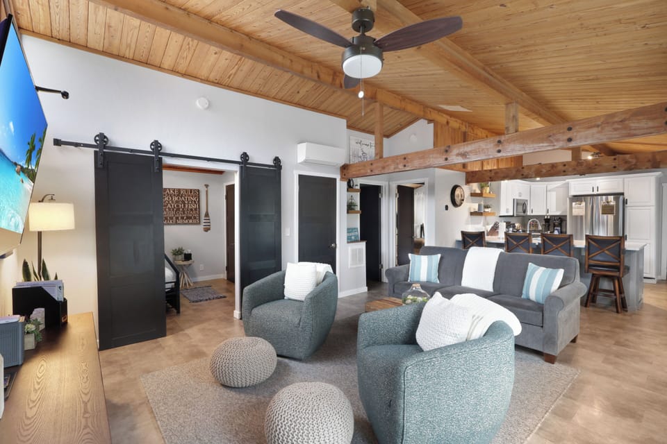 Unwind in your airy open-concept living space with vaulted wood ceilings, cozy seating, and modern farmhouse touches connecting you seamlessly to the full kitchen and dining area.