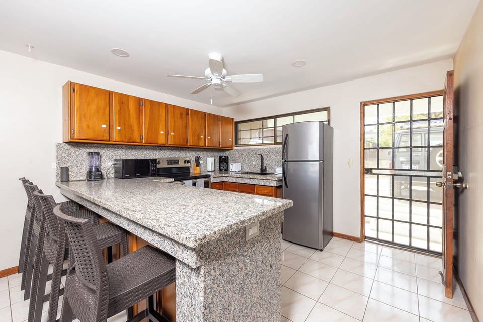 Fully furnished kitchen with microwave, electric stove, refrigerator, utensils, 
