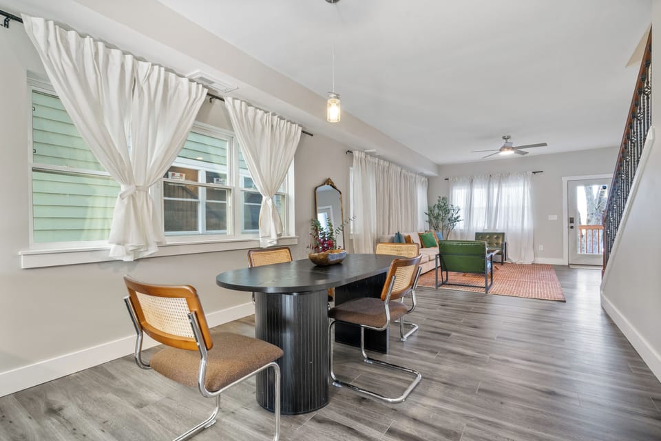 Dining nook with black table, retro chairs, and bright window-lit open layout.
