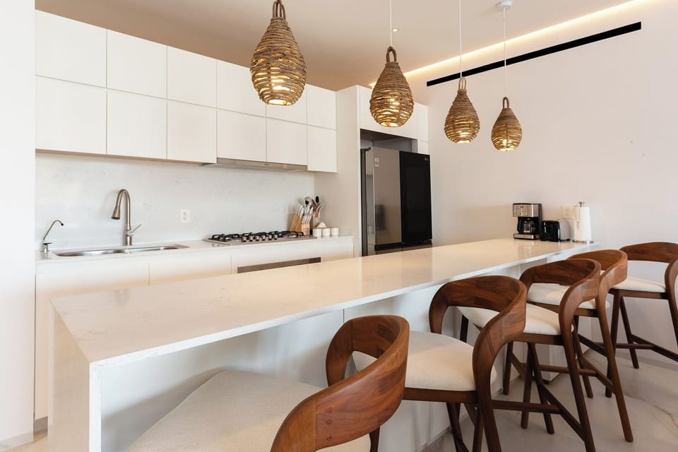 La cocina está diseñada para combinar funcionalidad y estilo. Cuenta con una elegante barra central con capacidad para seis lugares, perfecta para disfrutar de comidas informales, reuniones familiares o simplemente compartir momentos especiales.
