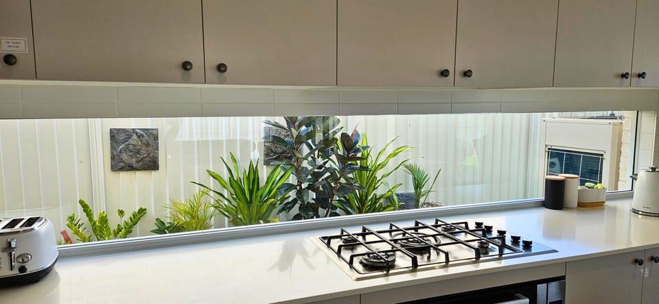 Cooking is a pleasure at Lotus, with a 900mm gas cooktop set against a window splashback that frames lush garden views. The design combines functionality with style, bringing natural light and a touch of greenery right into the heart of the home.