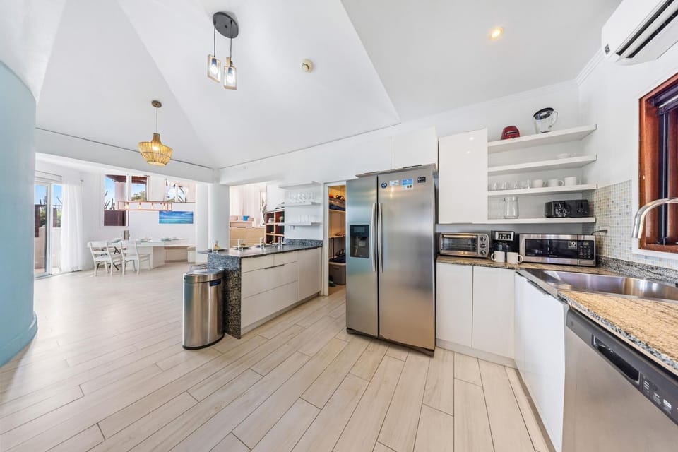 A sleek, sunlit kitchen with stainless steel appliances, a granite island, and warm wooden accents.
