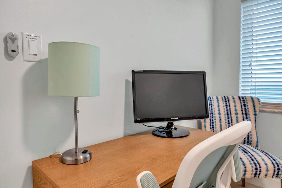 Compact desk setup w/ TV & lamp, ideal for light work or planning the day.