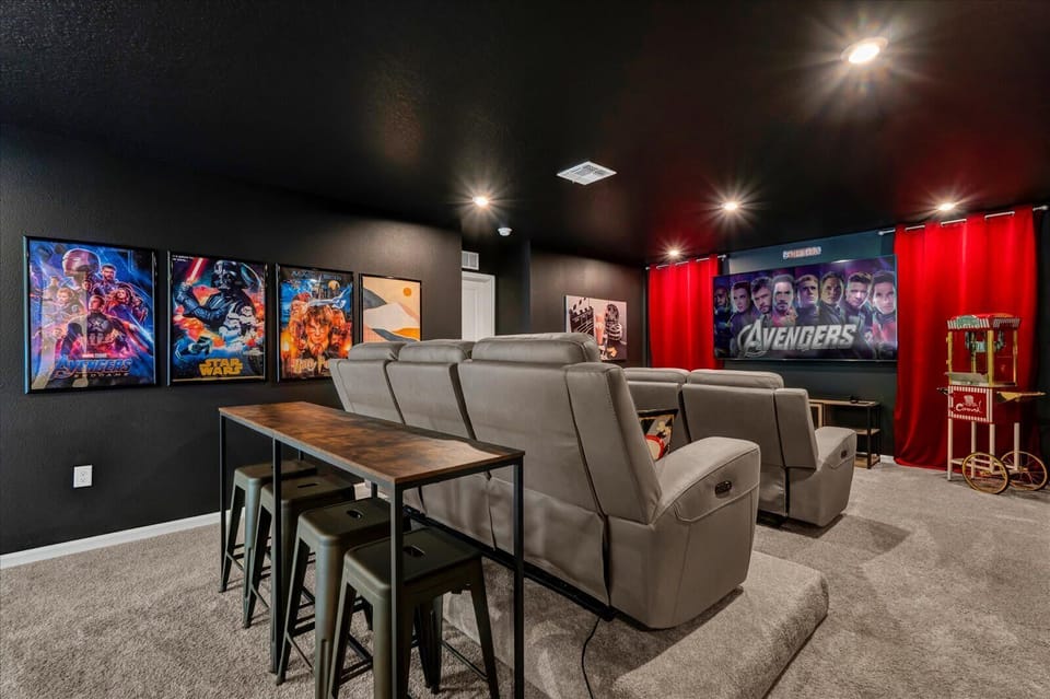 Experience the ultimate movie night in this private home theater with plush recliners, a large screen, and a vintage popcorn machine.