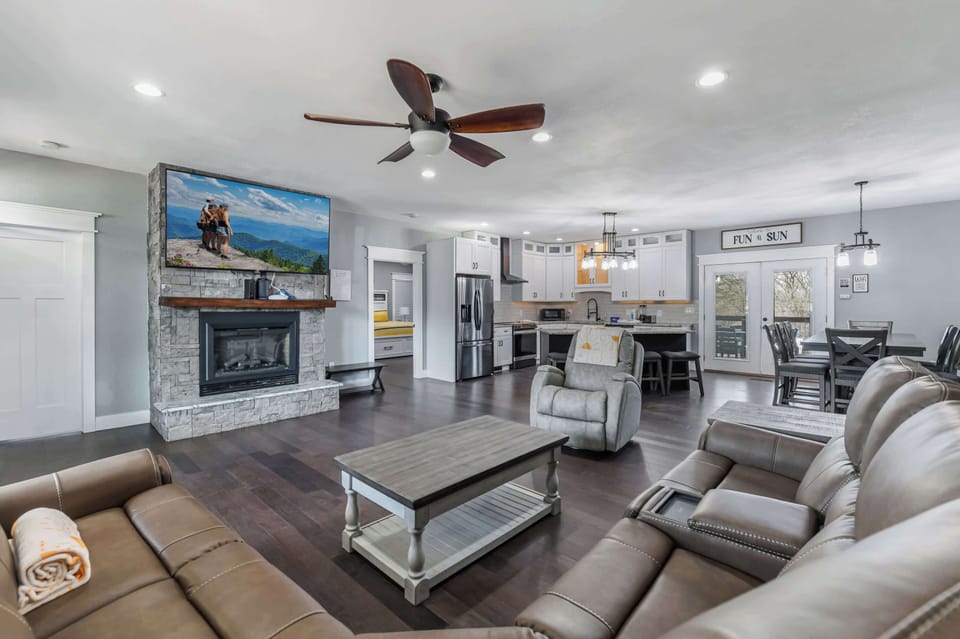 Open-concept living area with a stone fireplace and modern kitchen.