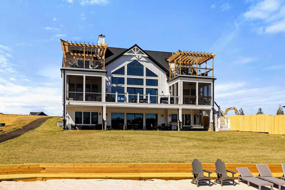 Elegant Lakefront Home: A breathtaking three-story retreat featuring expansive windows, multiple balconies with pergolas, and seamless indoor-outdoor living, all overlooking a private sandy beach and Lake Anna.