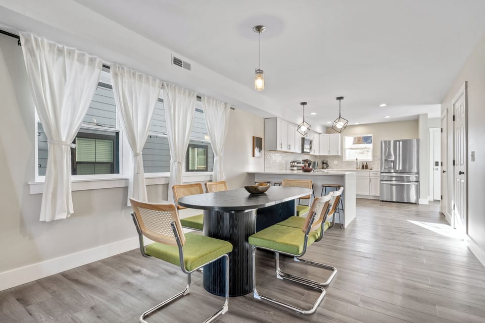 Airy dining with black table, 6 chairs, and floor-to-ceiling window curtains.
