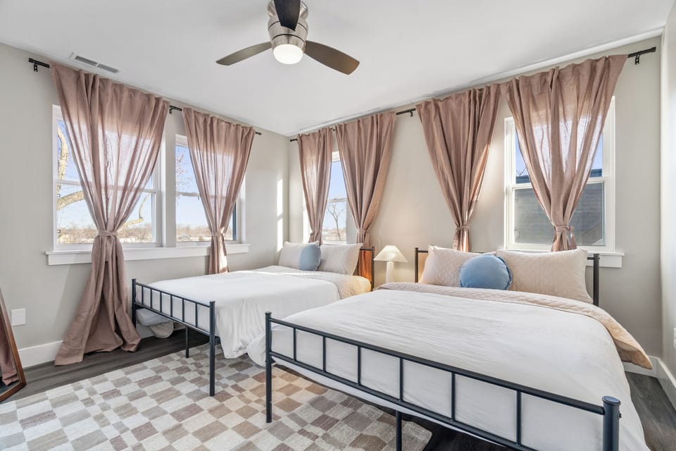 Bright room with 2 queen beds, 7 tall windows, blackout curtains, and a mirror.
