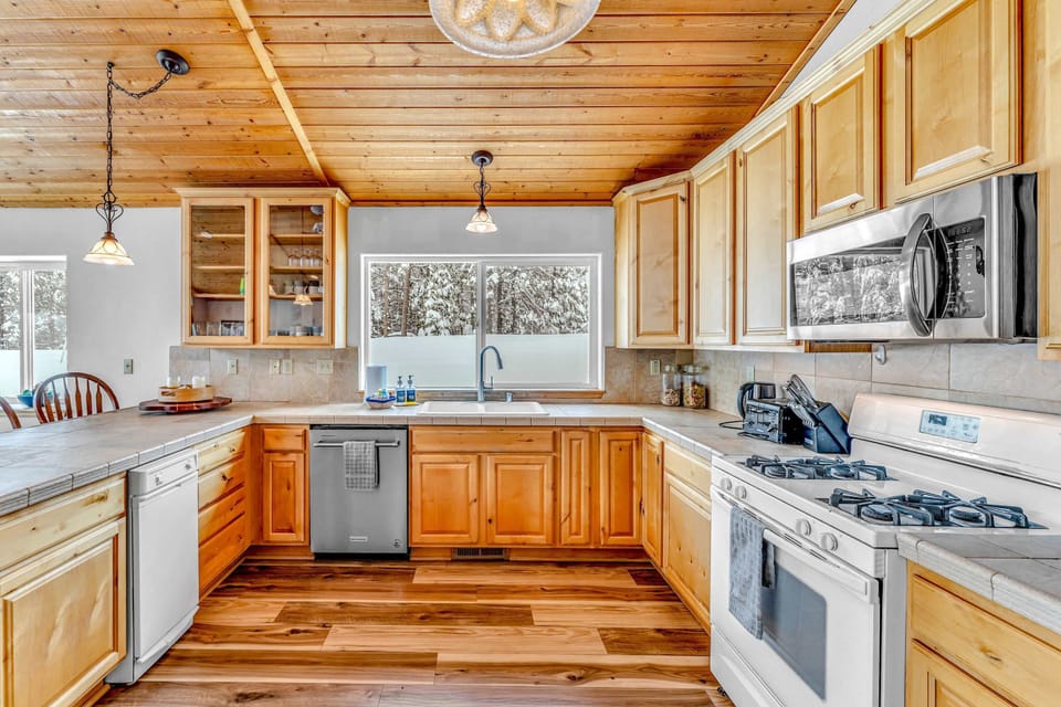 Kitchen: Keurig, drip coffee maker, cooking utensils, tableware, wine glasses, toaster, cutting boards, and knives

