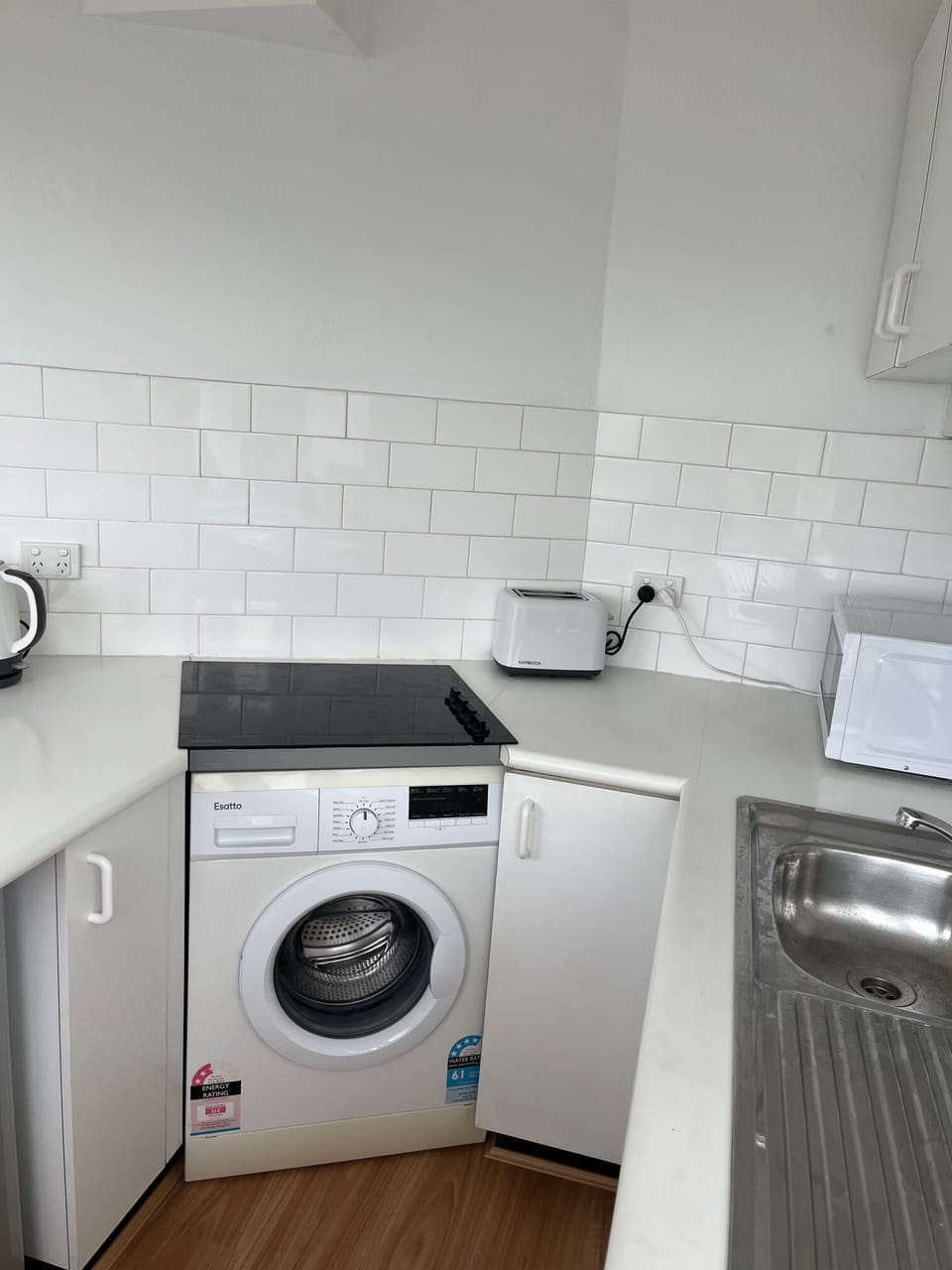 Full kitchen with washing machine, cooktop, kettle, toaster, microwave