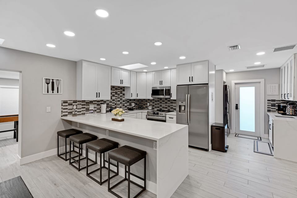 A sleek, open-concept kitchen with stainless steel appliances, elegant countertops, and a spacious breakfast bar with seating for four. Perfect for cooking. 