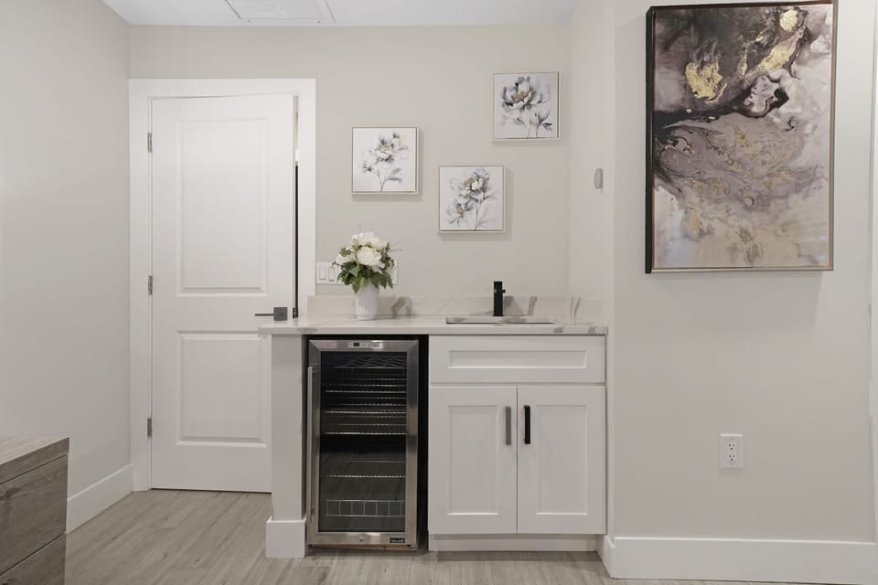 A beautifully designed wet bar with a built-in wine cooler, sleek cabinetry, and artistic accents, perfect for entertaining or enjoying a quiet drink.