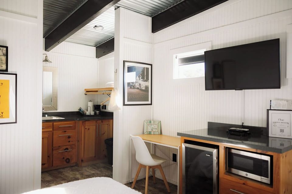 A sleek kitchenette, a dedicated workspace, and a mounted flat-screen TV—perfect for both relaxation and productivity.