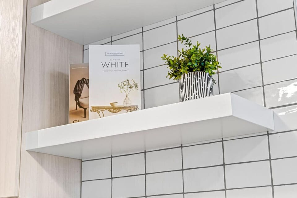 This bright and welcoming bathroom invites you to freshen up in comfort. Enjoy the forest-inspired shower curtain that adds a calming touch to your routine, complemented by the cozy rug underfoot and sparkling clean fixtures.