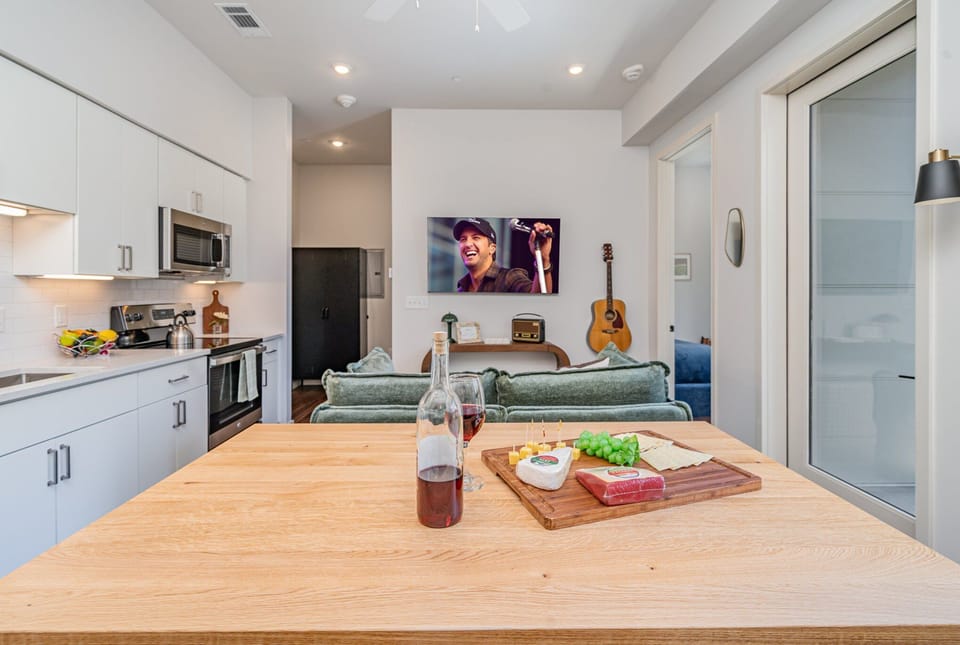 Kitchen with sleek white cabinetry, stainless steel appliances, and a butcher block island, perfect for preparing meals or enjoying a quick bite.