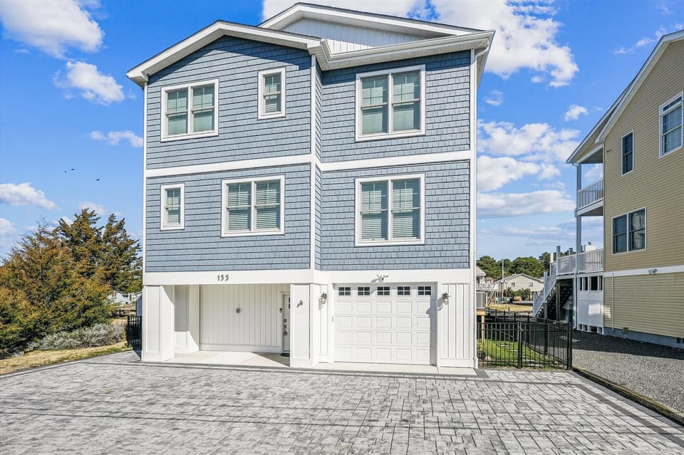 Charming coastal-style home with weathered shingle siding and modern amenities, situated in a peaceful residential neighborhood.