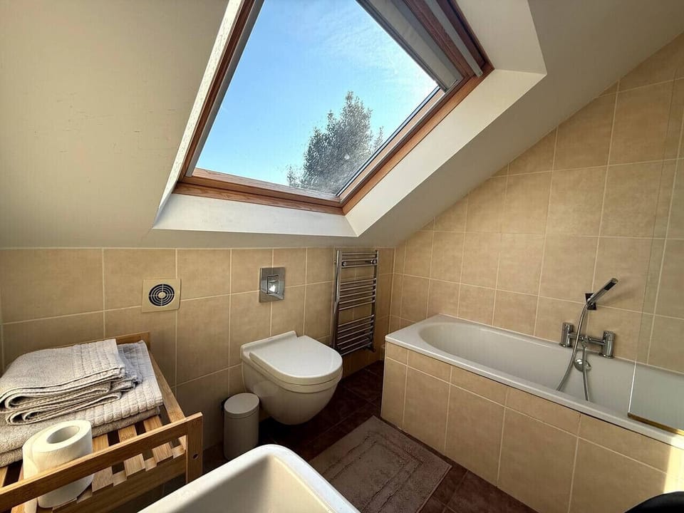 Skylit bathroom with tub and feature wall tiles