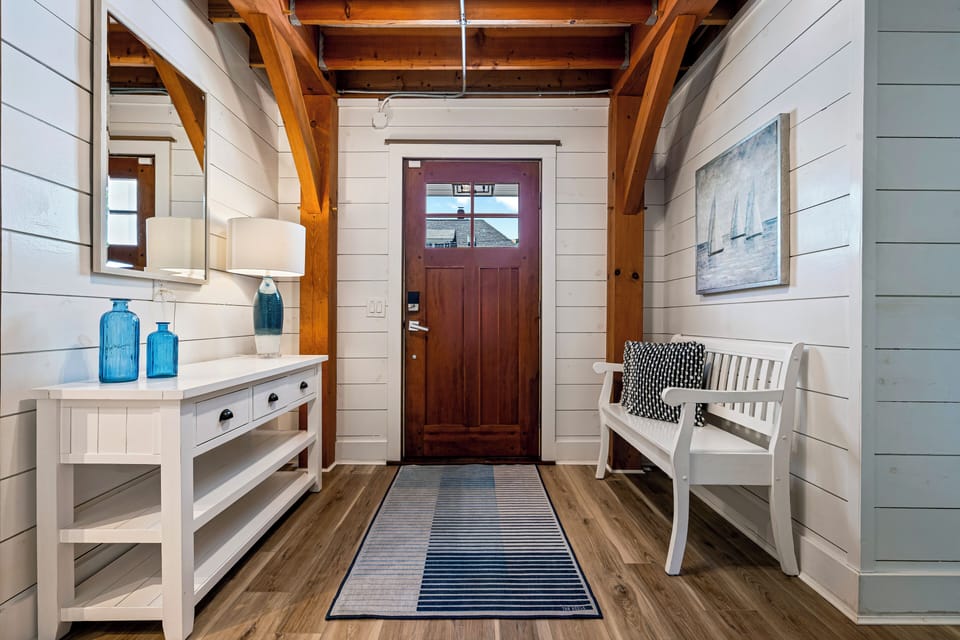 Entryway with wooden door, white walls, bench, and blue accents.