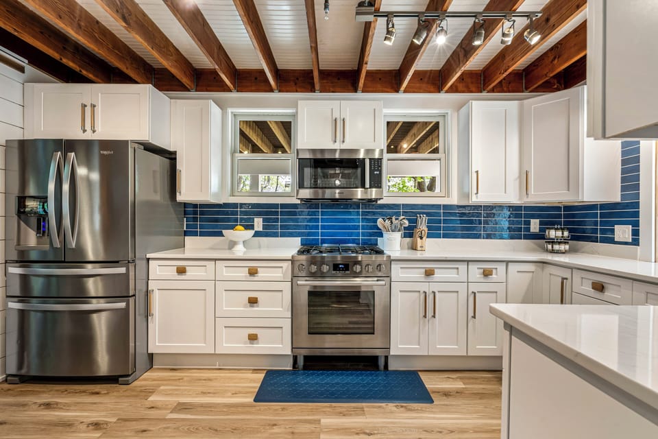 Bright kitchen with white cabinets, appliances, and wooden ceiling.