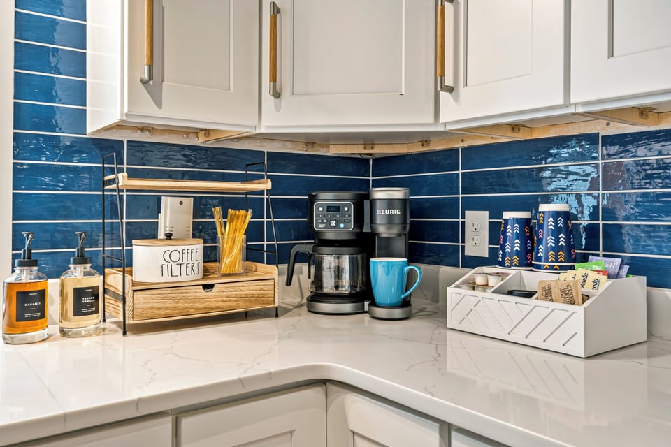 Kitchen with coffee station, blue tiles, white cabinets, and organized setup.