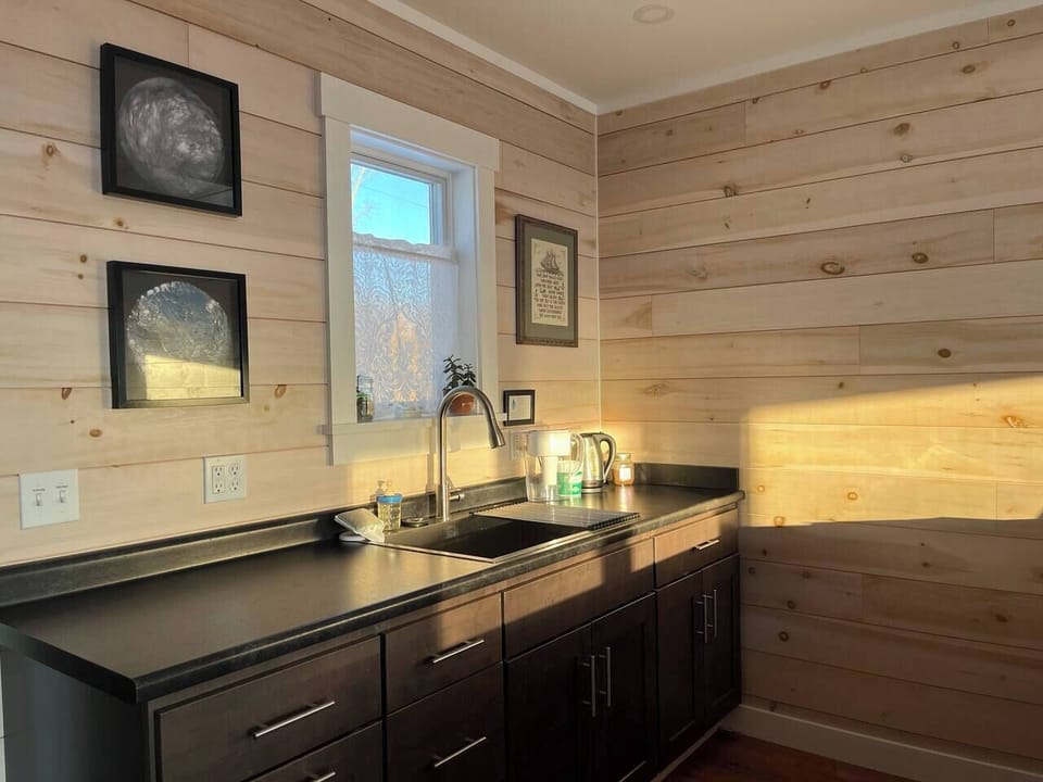 Sunny kitchenette with sea art, kettle, and pour-over—perfect for your morning coffee ritual.
