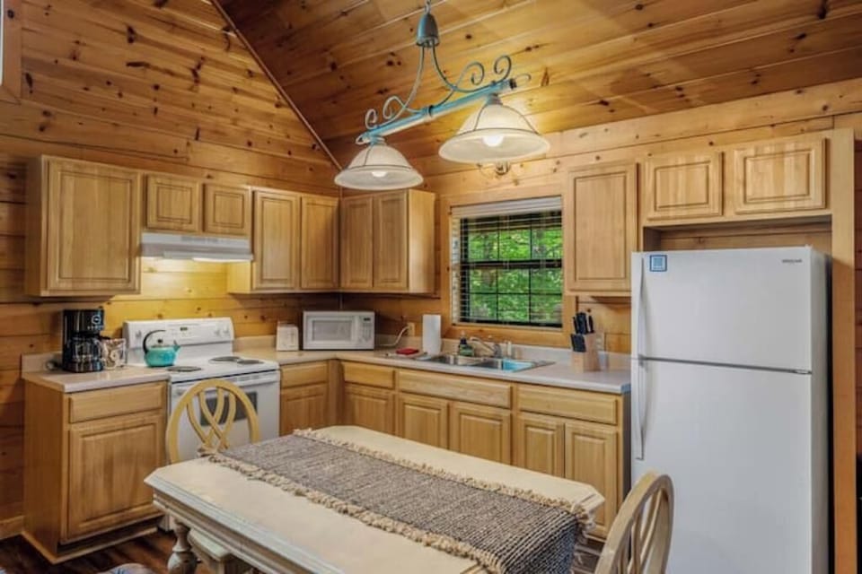 Full kitchen with refrigerator, stove, microwave, dishes, and dining area