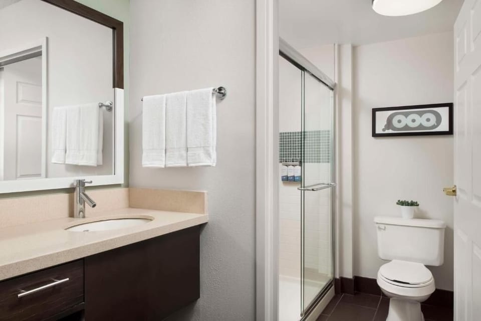 Refresh under a glass shower with plush towels and bright vanity.
