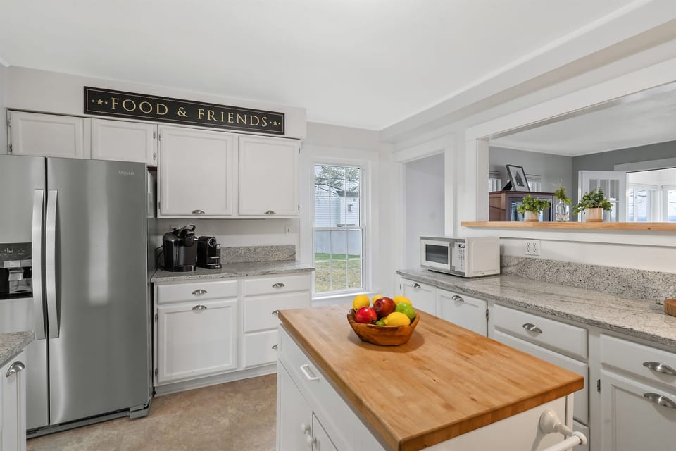This well-lit kitchen offers a sleek, open layout with a large fridge, coffee maker, and plenty of counter space for your culinary creations. Perfect for family meals or a quick coffee break!