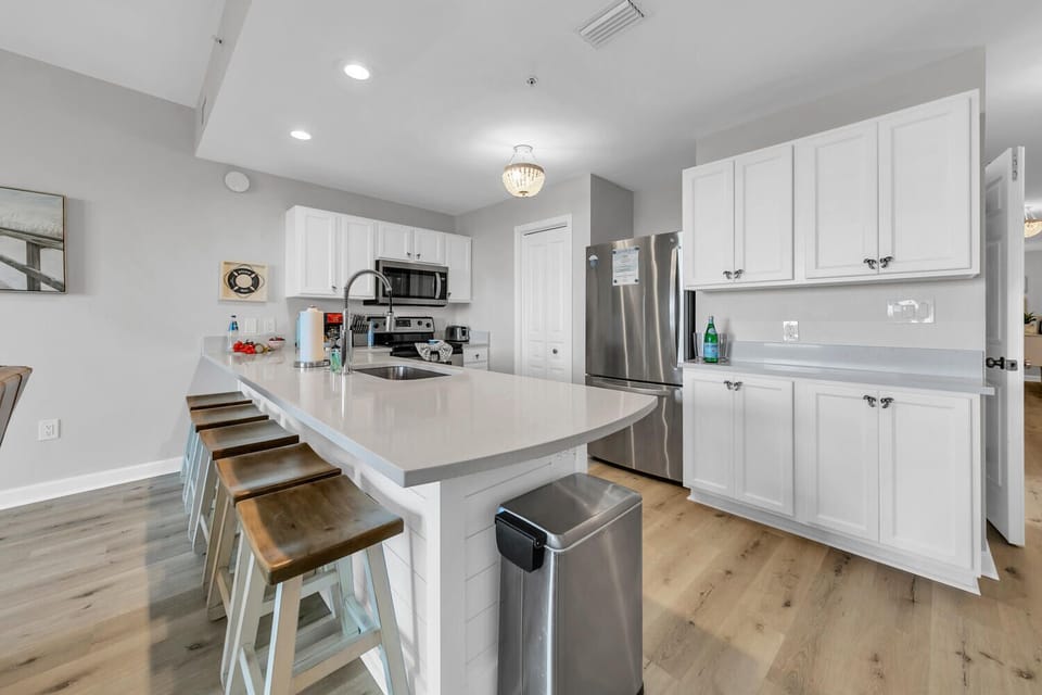 Your sleek kitchen awaits with white quartz counters, stainless steel appliances, and breakfast bar seating for memorable morning meals.