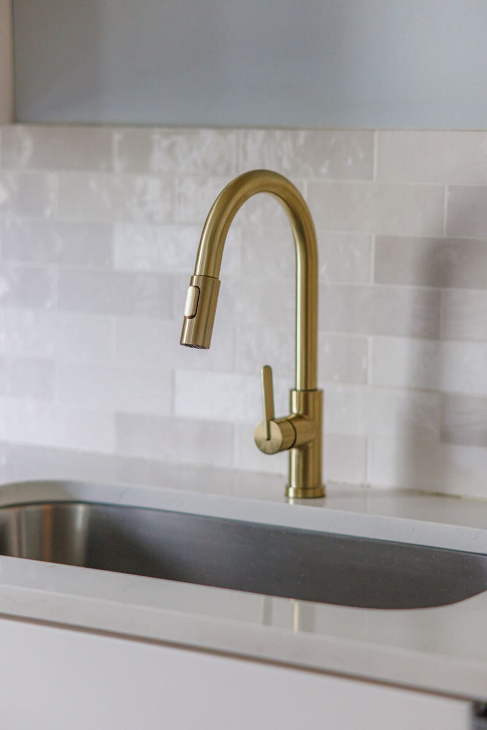 A pull down brass faucet paired with a deep stainless sink