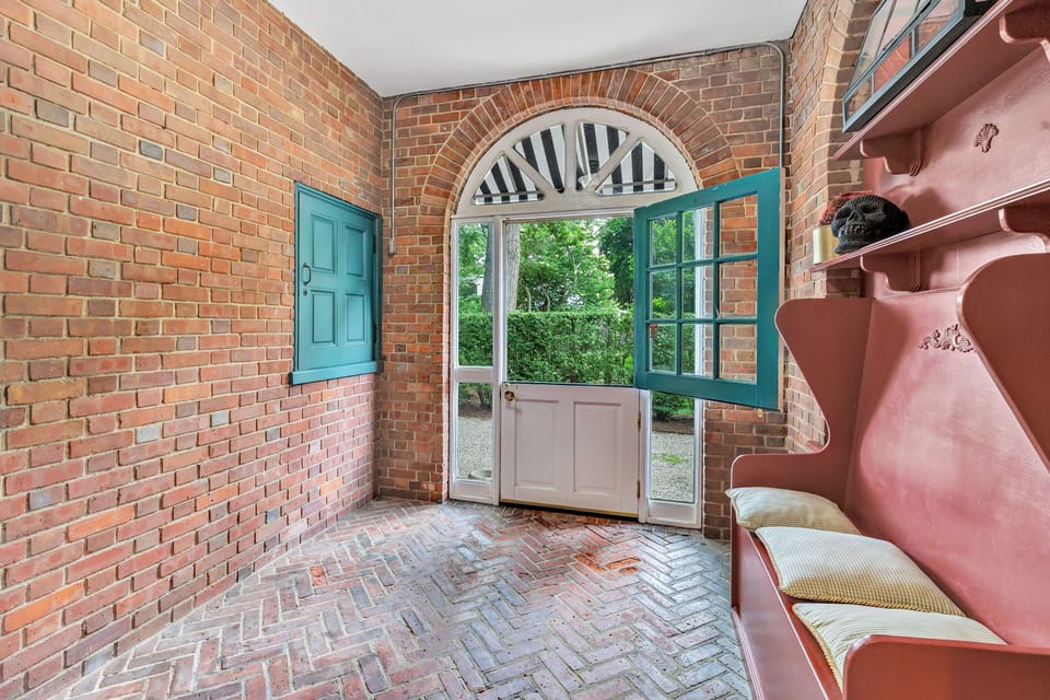Step into charm with this inviting mudroom, featuring exposed brick walls, a herringbone floor, and a classic Dutch door. A cozy and functional entryway perfect for welcoming guests or storing outdoor gear.
