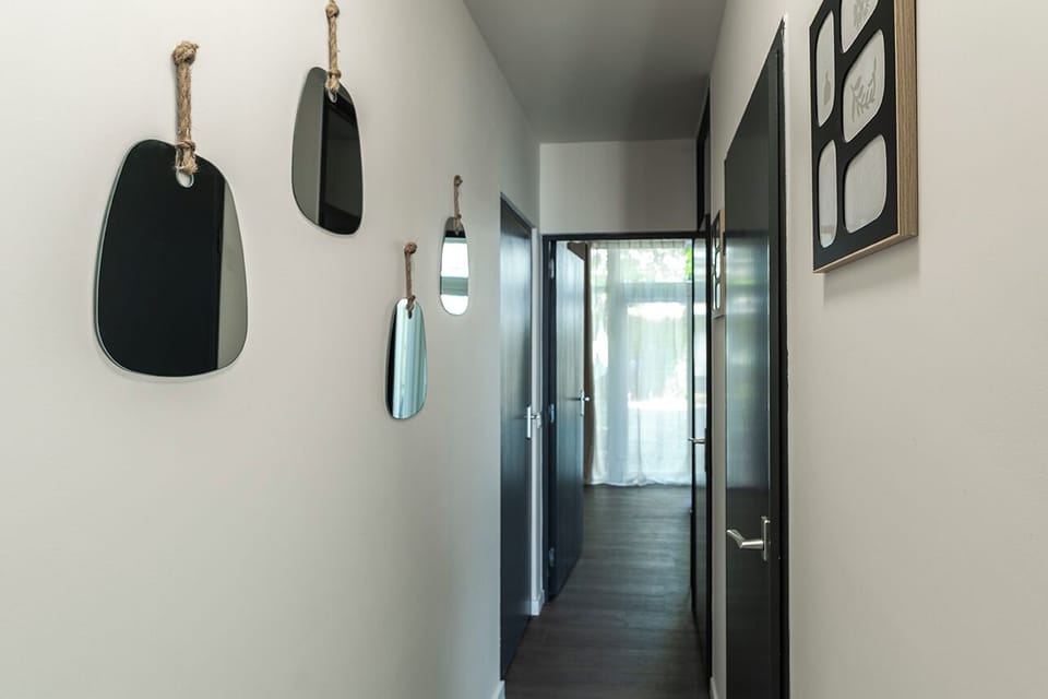 A bright and stylish hallway with playful mirrors leading to a cozy retreat.