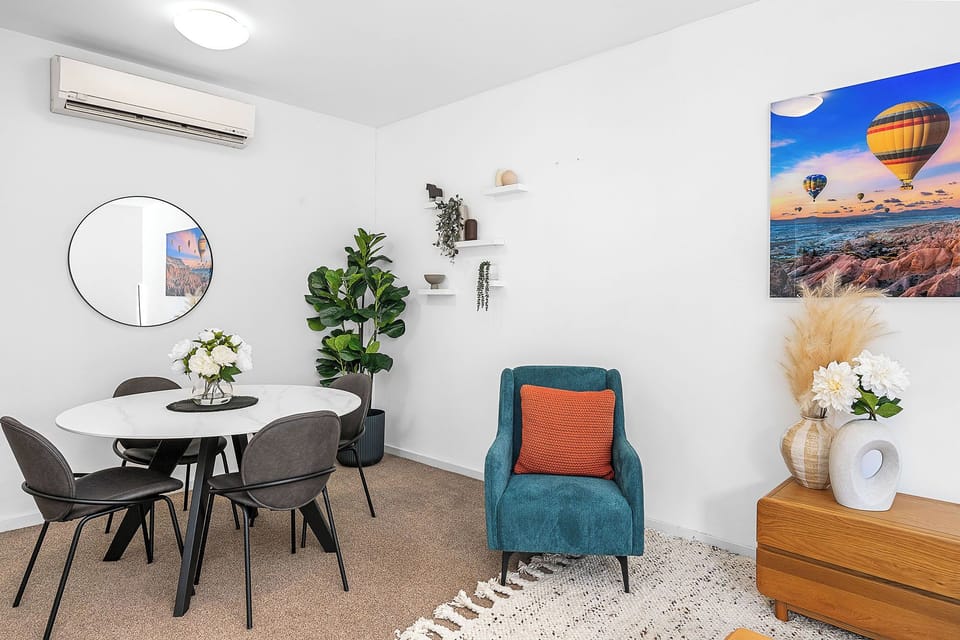 Enjoy meals in our cozy dining spot. Teal armchair adds a fun touch, and art brings a smile.