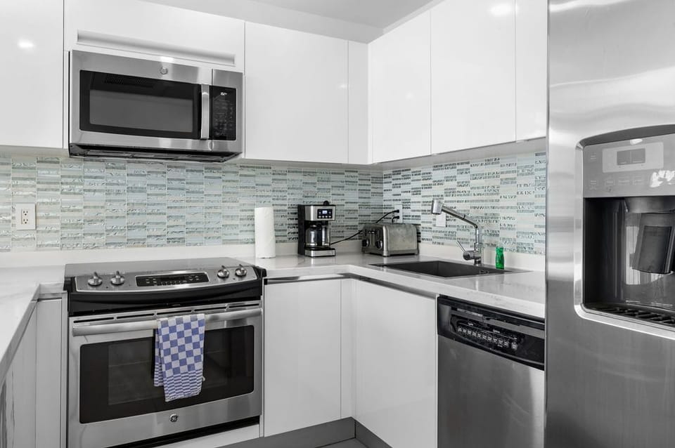 Your modern kitchen features sleek white cabinetry, stainless appliances, and a chic glass tile backsplash—everything you need to whip up vacation meals with ease.