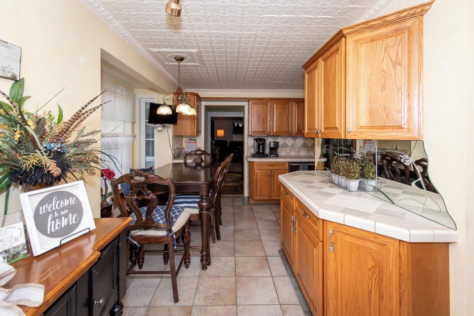 Picture yourself preparing meals in this fully-equipped kitchen, complete with tile countertops, warm wood cabinetry, and all the appliances you need. Gather around the dining table for memorable meals together.