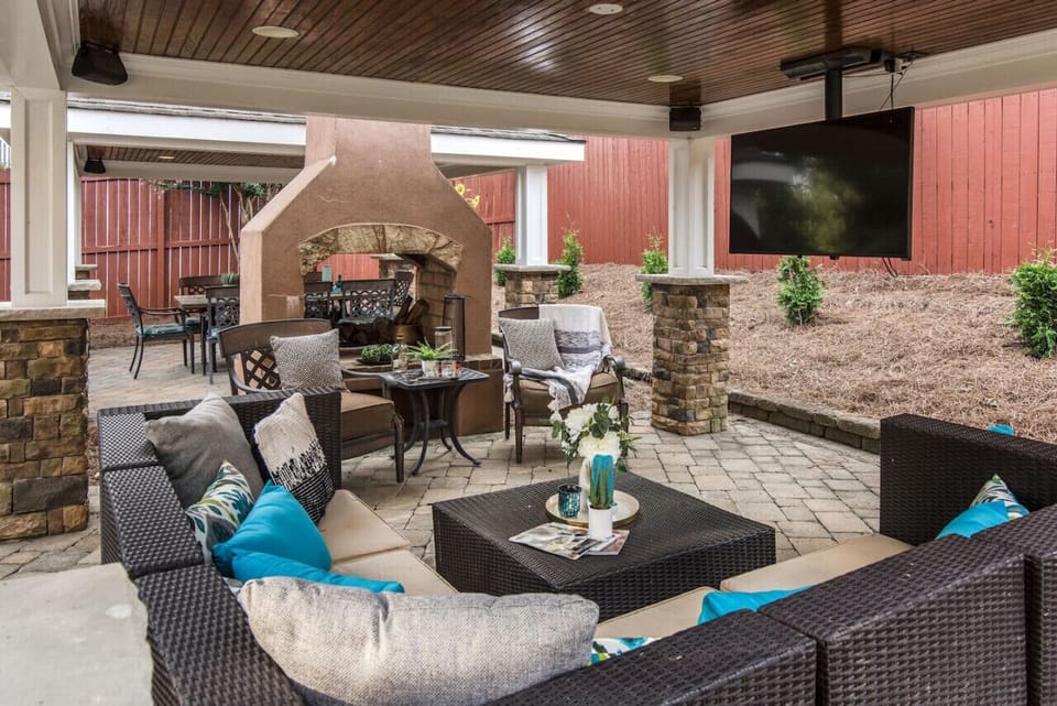 Two covered patio cabanas with a large fireplace, flat screen TV, couch seating, and a dining table with space for 8.