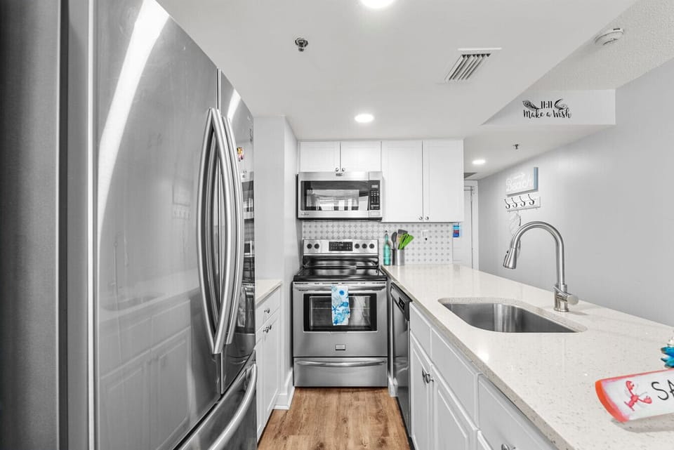 A fully equipped kitchen features stainless steel appliances, quartz countertops, and a sleek backsplash for stylish meal prep.