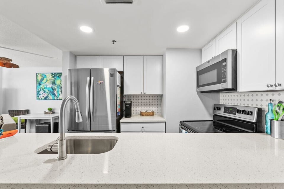 A fully equipped kitchen features stainless steel appliances, quartz countertops, and a sleek backsplash for stylish meal prep.