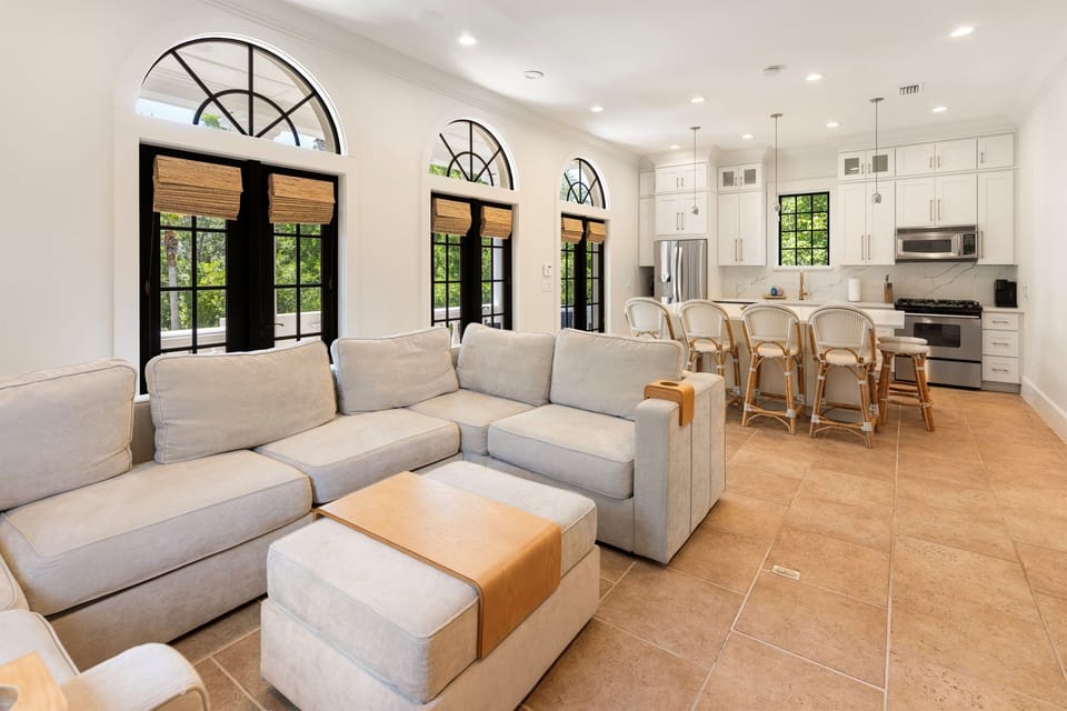 Relax in your bright open living space where arched windows frame lush garden views and modern comfort meets elegant design.