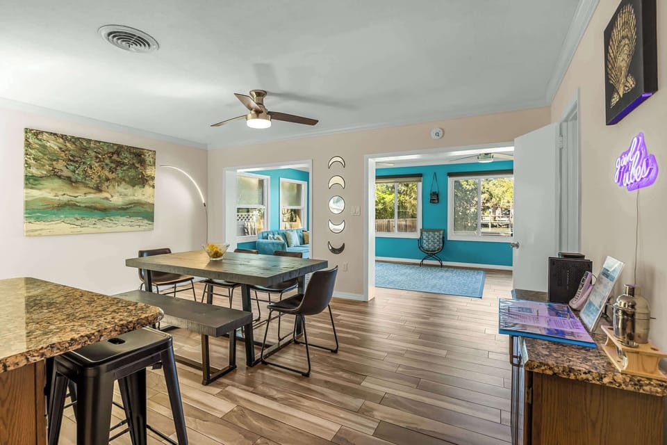 Dining area with modern ceiling fan and views into a bright turquoise living space.