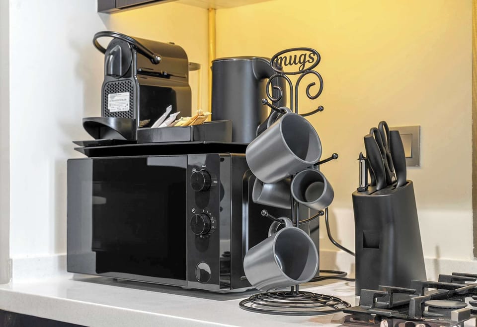 Stylish kitchen with espresso bar, microwave, kettle & sleek mug stand, perfect for mornings.