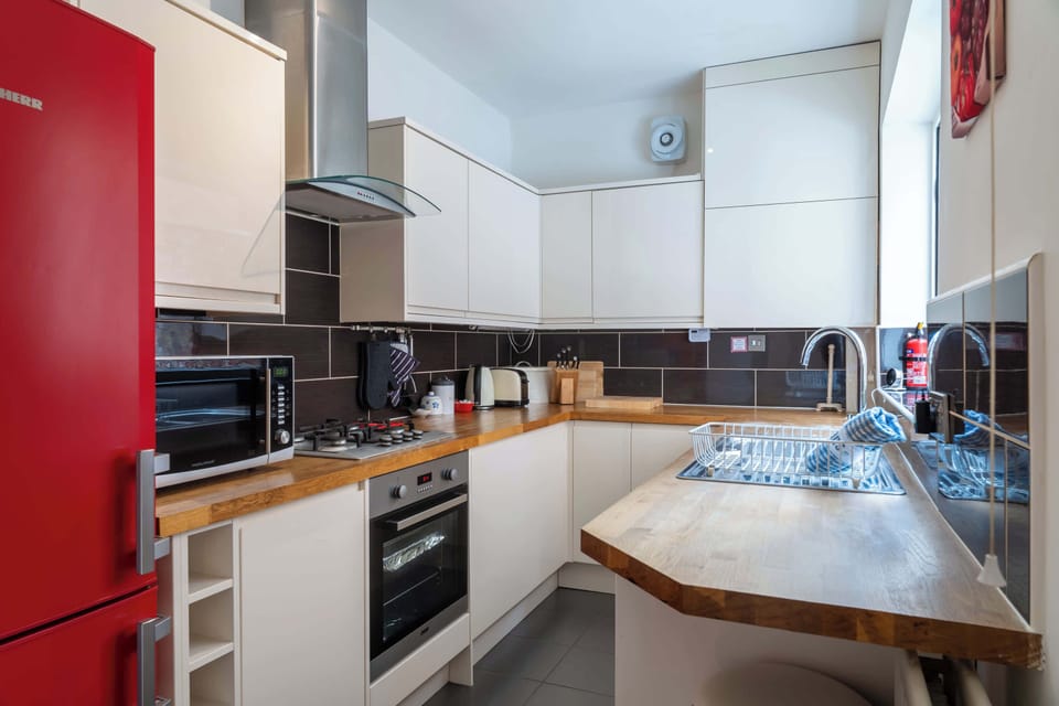 Well-equipped kitchen with bold design touches, including a striking red fridge, wooden countertops, and modern appliances – ideal for cooking and casual dining