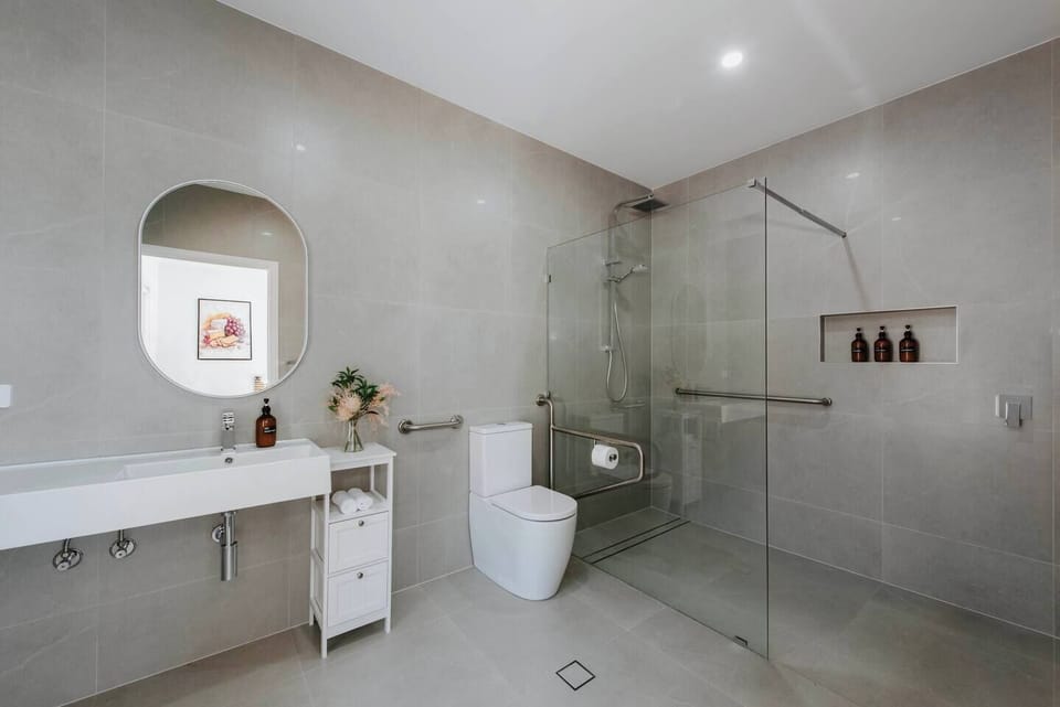 This thoughtfully designed bathroom prioritizes accessibility, featuring grab bars and a spacious walk-in shower for added comfort and convenience.