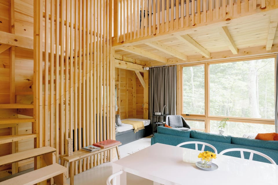 Cabin has open plan with living, alcove, dining, and stair to loft above.