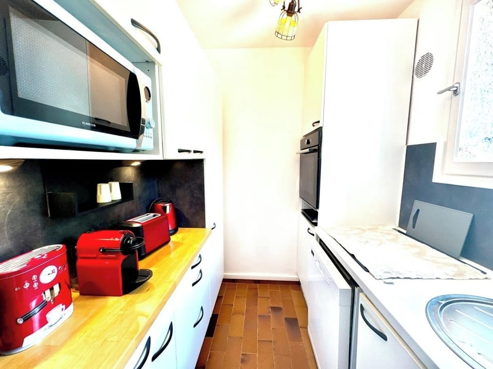 Une cuisine bien équipée pour les amateurs de café et de bons plats. Les appareils rouges ajoutent une touche chaleureuse et moderne. L'espace, bien optimisé, permet de cuisiner aisément malgré sa taille compacte. 